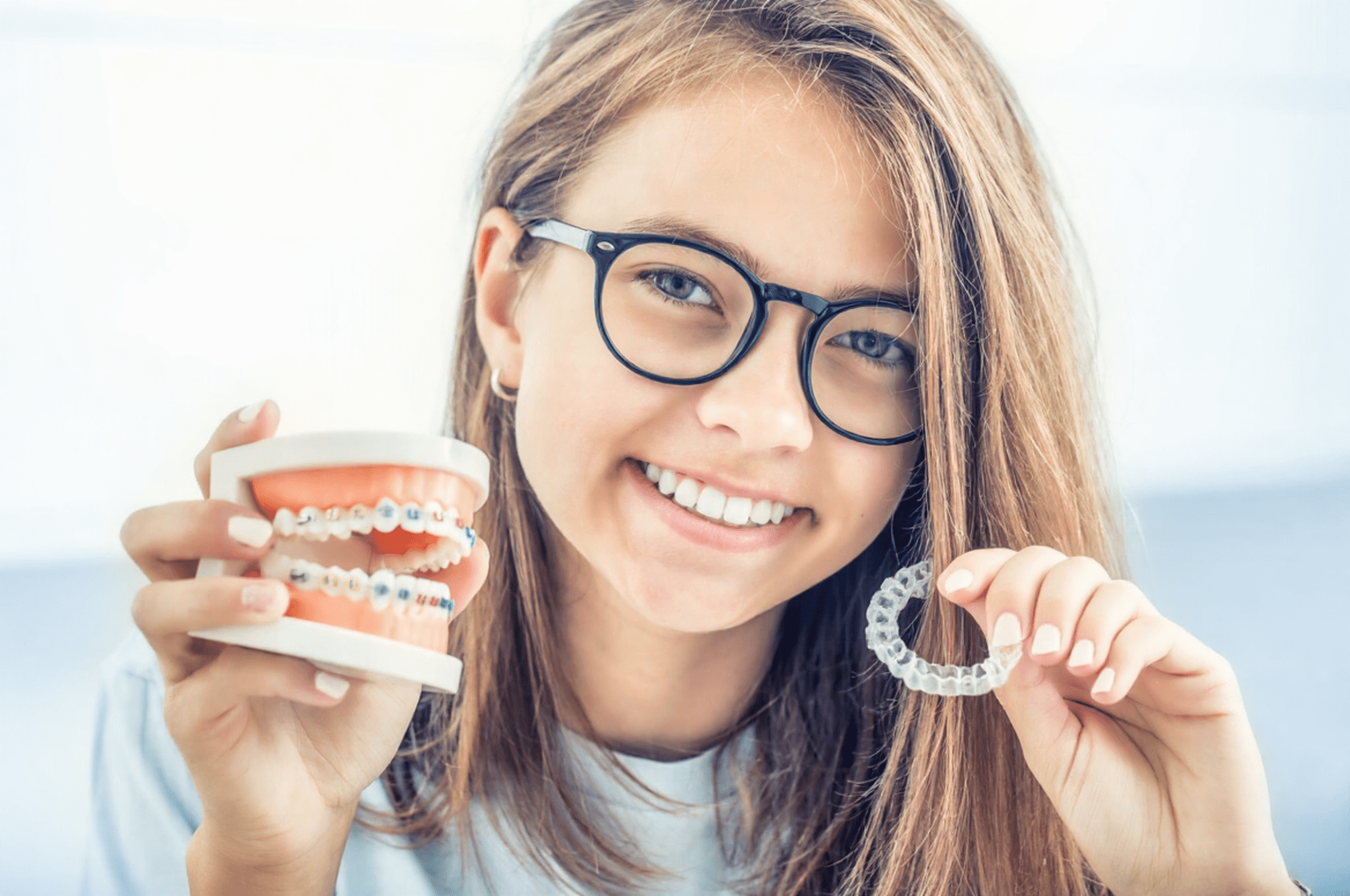 Woman holding braces model and clear aligner showing treatment options