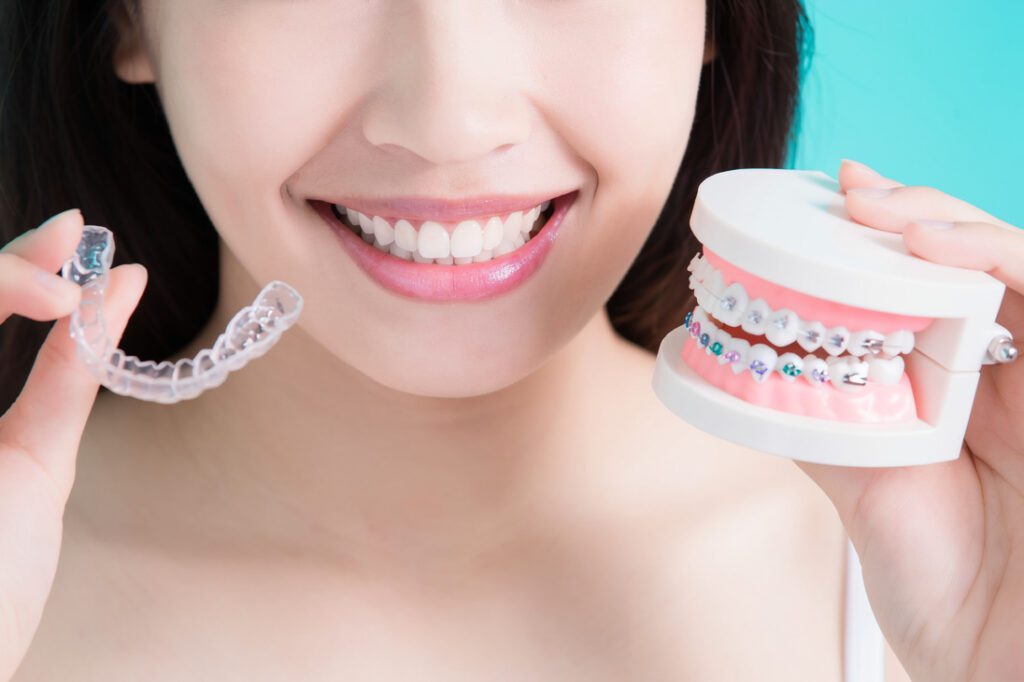 Invisalign vs braces comparison for adults showing clear aligners and traditional braces model
